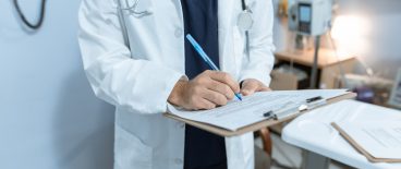 Doctor taking notes on a clipboard in medical exam room