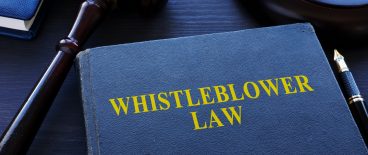 image of book titled whistleblower law on desk with gavel, pen, glasses