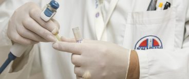 image of gloved medical personnel with testube and equipment