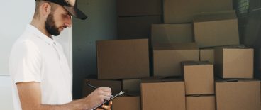 Worker with notepad and boxes in truck