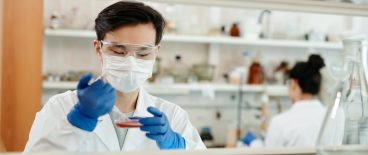 Laboratory worker with petri dish and syringe