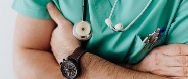 man in scrubs with arms crossed