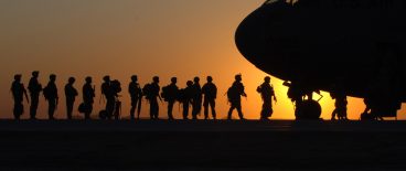 Military deploying into airplane with sunset in background