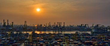 sunset image of containers and ships and equipment in background
