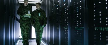 Image of two miliary men walking through a dimly lit server room