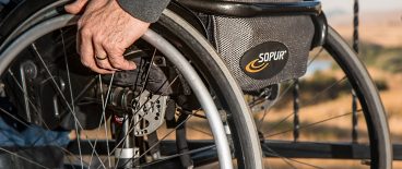 image of elderly man's hand on the side of a wheelchair