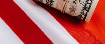image of money rolled up with rubber band and american flag