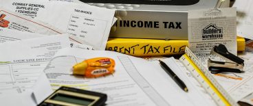 image of income tax book, files, invouces, pens , calclulator, and office supplies on desk