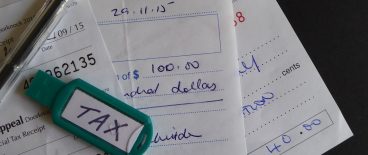 image of thumb drive marked tax with pen and receipts on gray surface