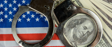 cuffs on top of hundred dollar bills and American flag