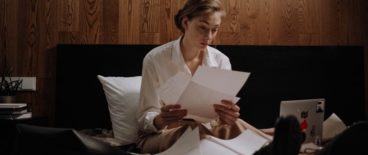 woman sitting in bed with documents in hands and on her lap