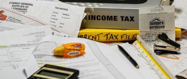 pile of papers and books with highlighter and calculator