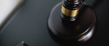 gavel resting on black wooden surface near two stacked, black binders