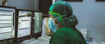 a scientist in full lab equipment working on a computer