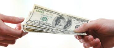 person handing another person dollar bills