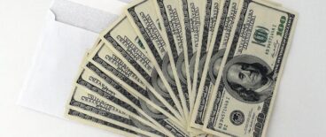 hundred dollar bills fanned out on top of a white envelope