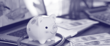 piggybank and a stethoscope on a laptop with money on the side