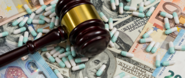 Judge's gavel resting on a pile of money with scattered medicine pills around it